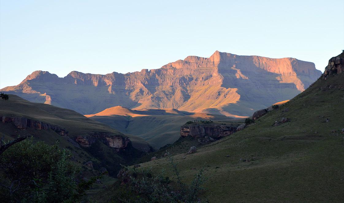 The Drakensberg Mountain Range lit by golden light at sunset.