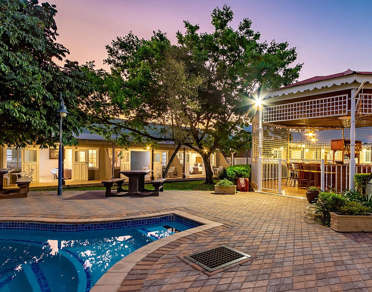 The outdoor pool and garden area of Little Pilgrims Boutique Hotel at dusk.
