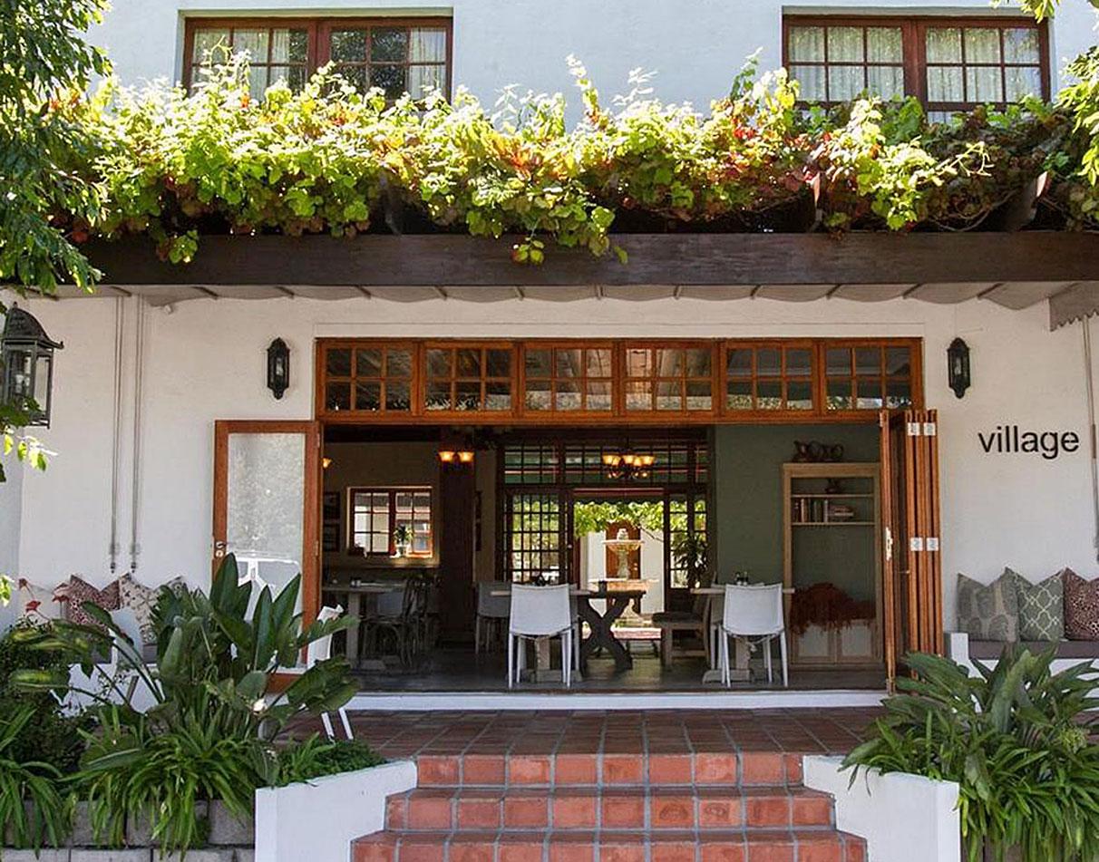 Main entrance of The Noordhoek Village hotel, decorated with plants.