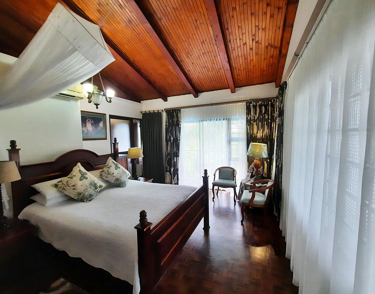 A double room at St Lucia Wetlands Guesthouse with a four-poster bed, wooden ceiling and hardwood floors.