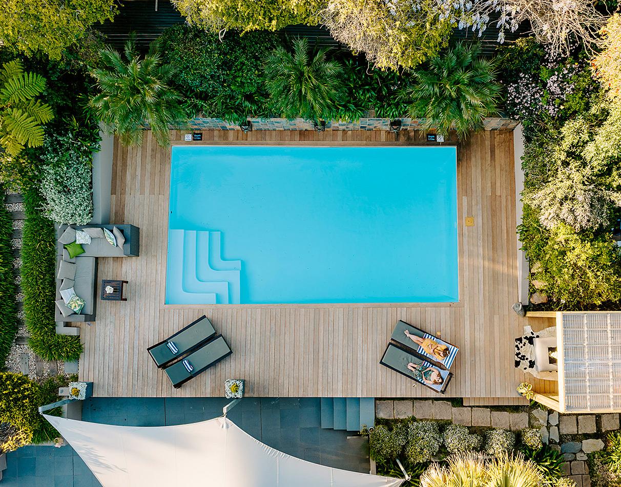 Aerial view of a lush garden swimming pool with loungers at Kanonkop guesthouse on the Garden Route.