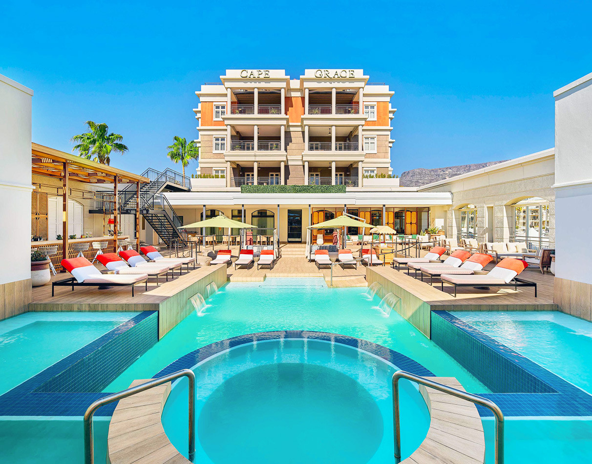 Cape Grace Hotel exterior with tiered swimming pools and sun loungers, Cape Town waterfront.
