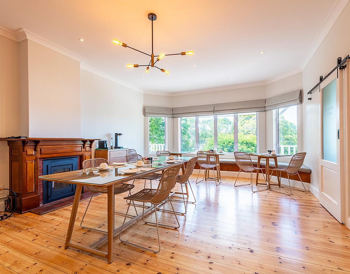 Bright communal dining area with fireplace and garden views at Hideaway guesthouse on the Garden Route.