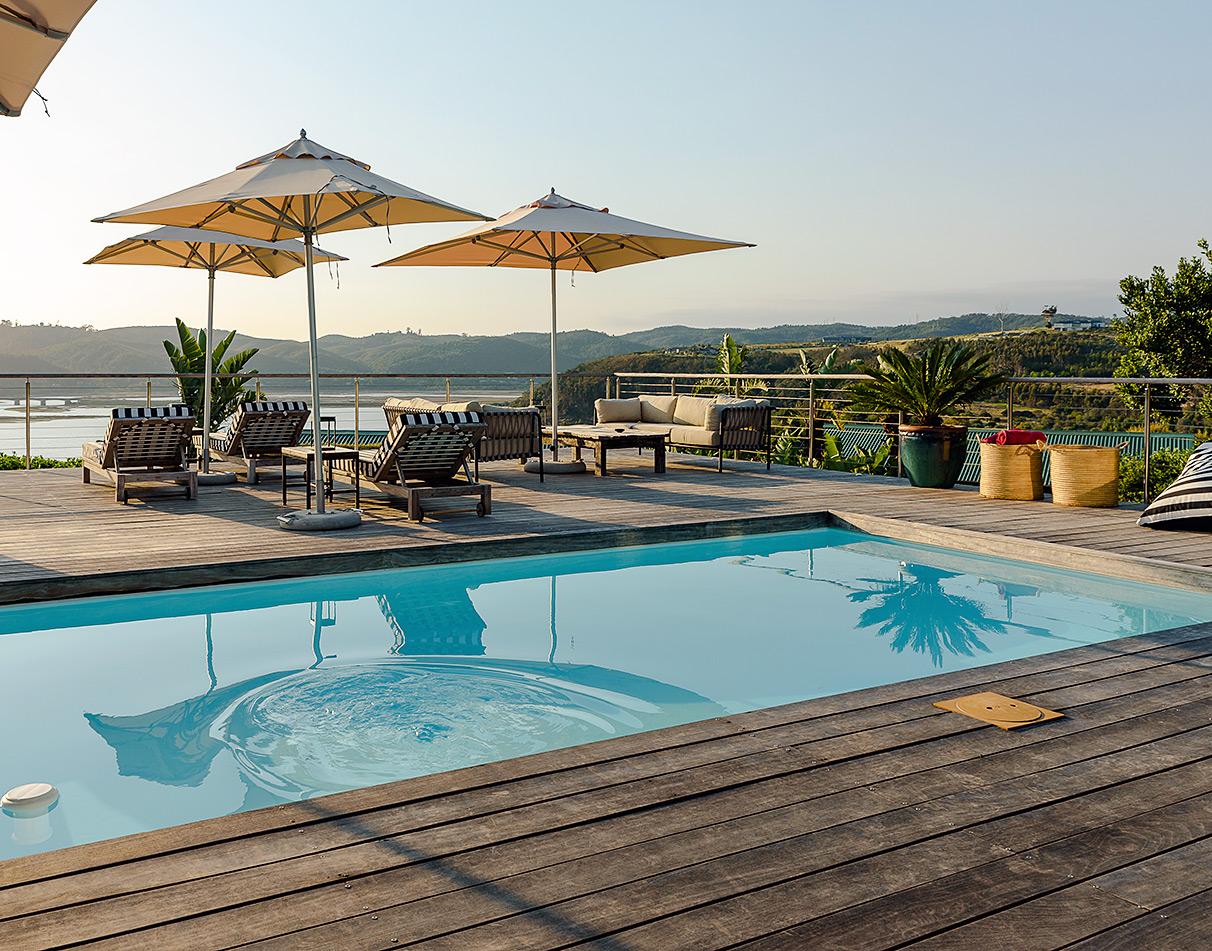 Pool deck with sun loungers and umbrellas overlooking the Knysna Lagoon at Elephant Hide guesthouse.