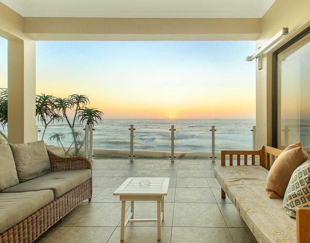 Fairlight Beach House terrace with seating overlooking the Indian Ocean at sunset.