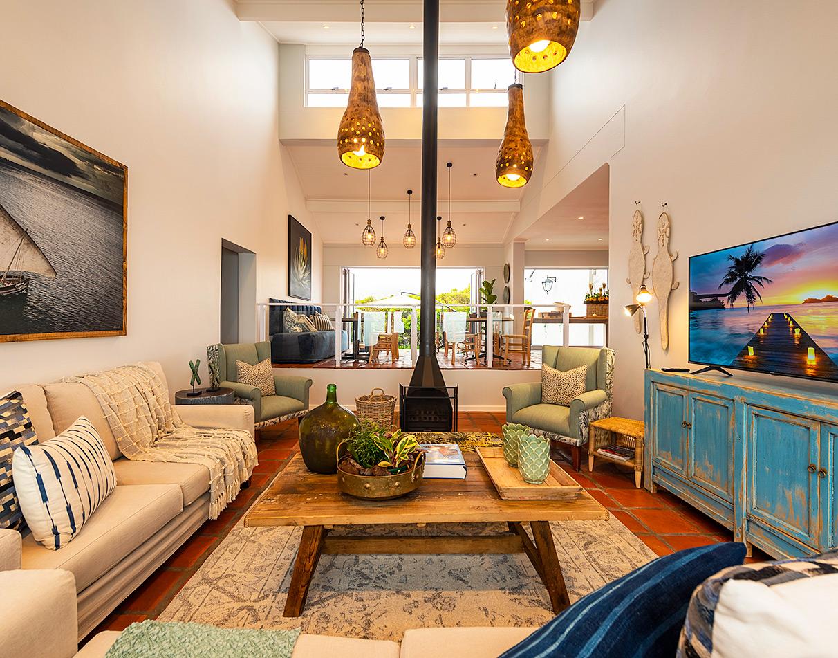 Mes Amis Guesthouse interior lounge with high ceilings, pendant lights, central fireplace and eclectic coastal décor on the Garden Route.