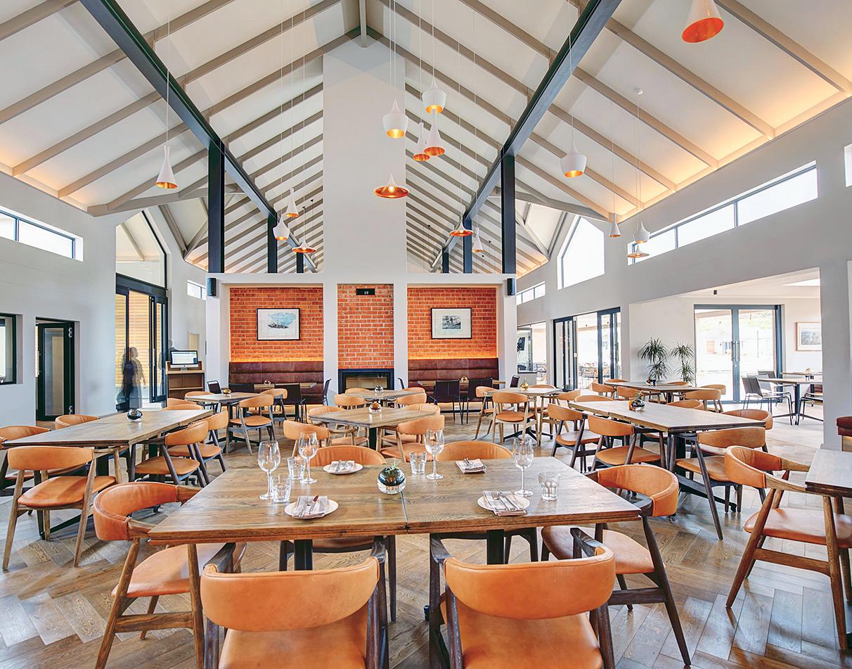 Stylish restaurant interior with vaulted wooden ceiling and leather chairs at Hollow Country Estate, Knysna.