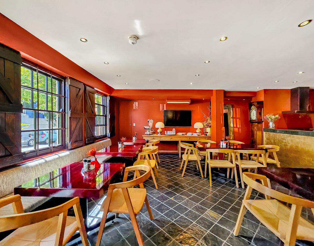 Cozy red-walled restaurant dining room with wooden tables and chairs in Cape Town.