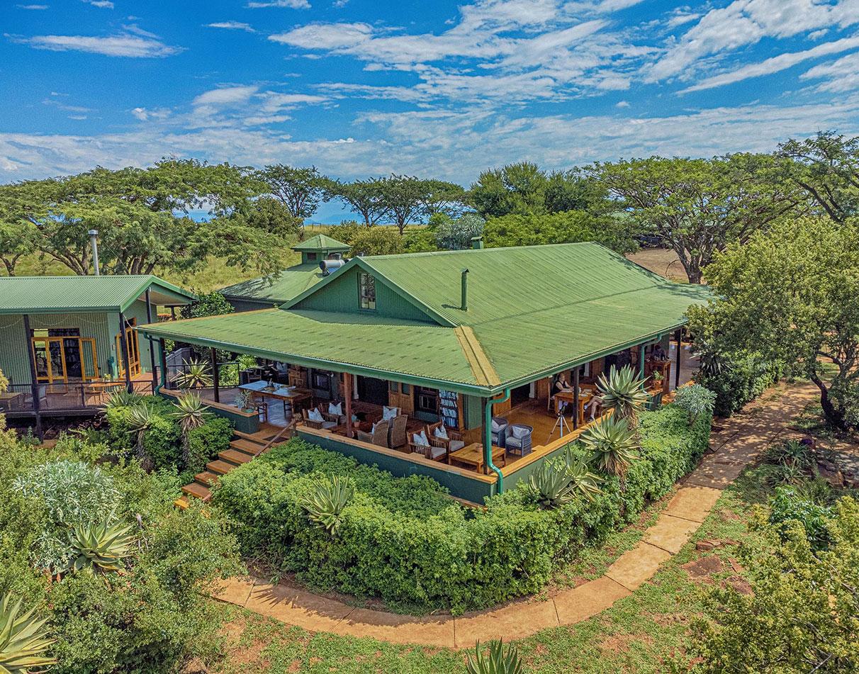 Aerial view of Three Tree Hill Lodge main building with green roof, wraparound veranda and indigenous garden.