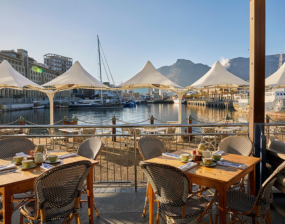 Waterfront restaurant terrace with view of Table Mountain and harbour boats at the V&A Waterfront, Cape Town.