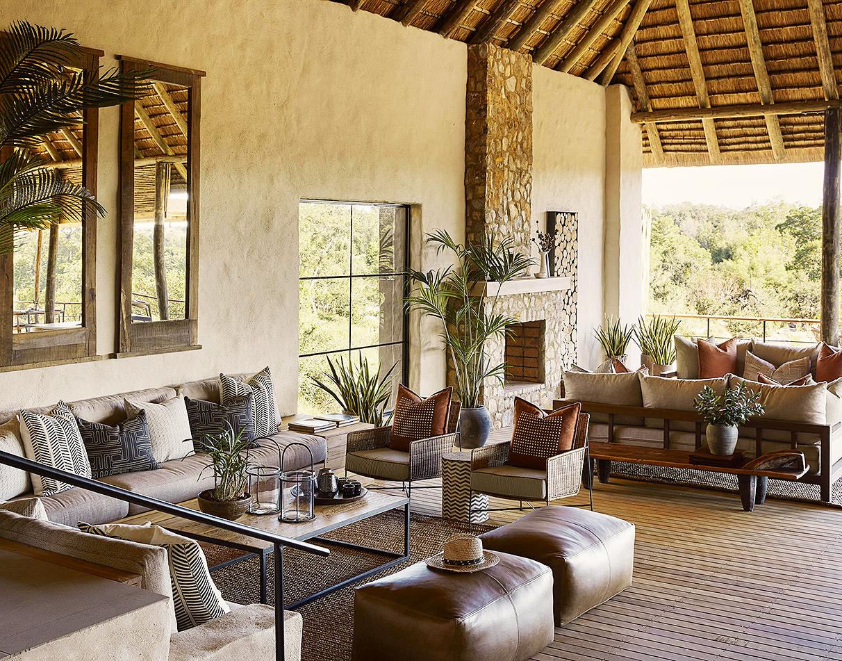 Open-air lounge at Londolozi Founders Camp with thatched roof, stone walls, and bush views.