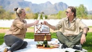 A couple enjoying a romantic wine tasting picnic in Stellenbosch, South Africa.