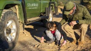 A guide and child tracking wildlife on foot at Shamwari River Dene, South Africa.