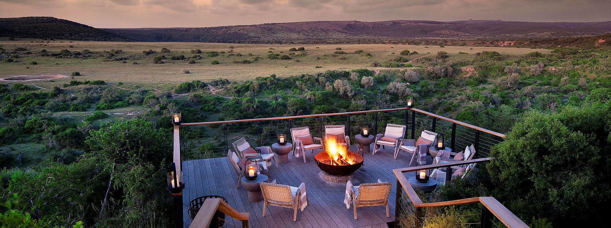 A fire pit terrace at Shamwari Sindile lodge overlooks the South African bushveld at sunset.