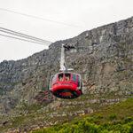 Red cable car ascending Table Mountain with Cape Town below.