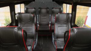 Interior of a small group tour vehicle with black leather seats.