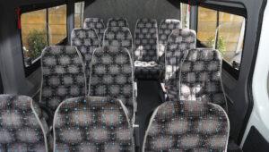 Interior view of a spacious tour van with rows of patterned seats, ideal for group travel.