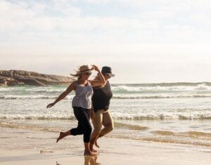 Two women running along the beach in South Africa having fun.