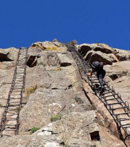 Person climbing a steep chain ladder on a rocky mountain in South Africa.