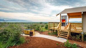 Africamps White Elephant outdoor hot tub, fireplace and wooden deck overlooking the bush and lake at sunset