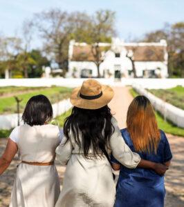 Three girlfriends enjoy a scenic walk at a wine farm.