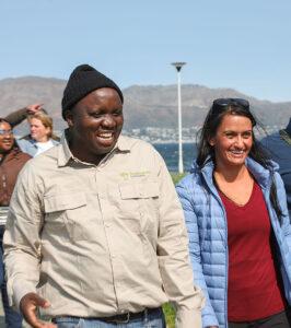 Guide and guest laughing together on a small group tour in South Africa, with mountains in the background.