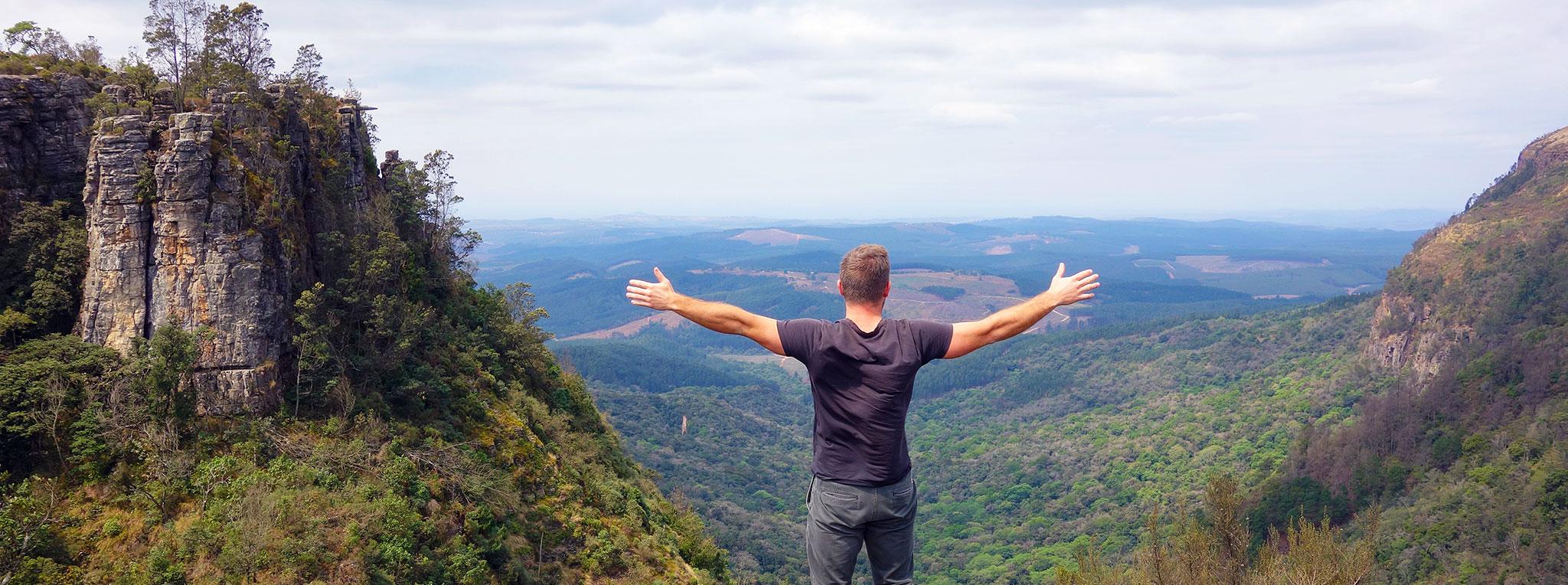 Man on a hike on the Panorama Route, stretching out his arms infront of God's Winodw.
