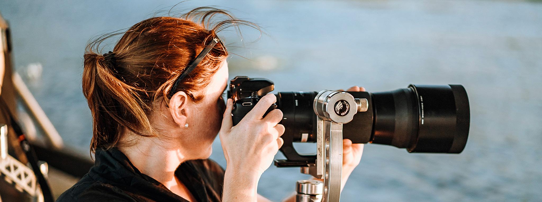 Woman on a photography boat safari capturing wildlife in the distance.