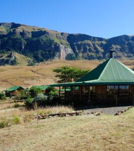 Greenfire Lodge Drakensberg cottage with green roof set against dramatic mountain scenery.