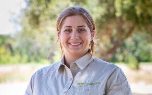 A smiling South Africa Experience team member, Alexandra in uniform outdoors.
