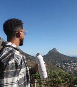 Hiker holding a water bottle with view of Lion's Head mountain in the distance, Cape Town.