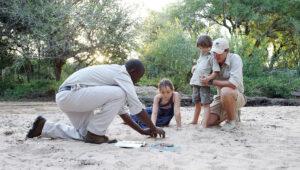 Children learning tracking skills with safari guides at Londolozi, South Africa.