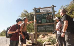 A group of hikers stand at the signboard for the Platteklip Gorge hike on Table Mountain.