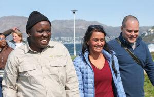 A South Africa Experience guide laughs with his group of guests while alking towards the beach.