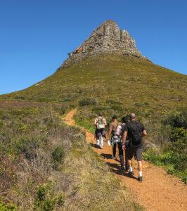 Hikers walking a trail toward the rocky summit of Lion's Head, Cape Town, South Africa.