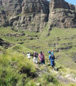 Hikers ascend a grassy slope in the Drakensberg Mountains, with their guide from Witsieshoek Mountain Lodge.