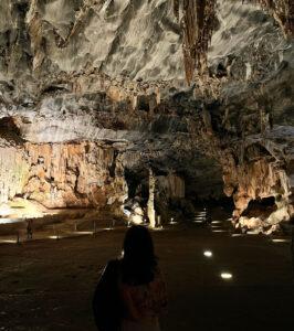 Visitor exploring stalactite chamber, Cango Caves, South Africa.
