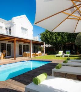 Bamboo Guest House pool and garden with sun loungers and umbrella.