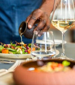 Chef plating a gourmet dish with wine at Ellerman House, Cape Town.