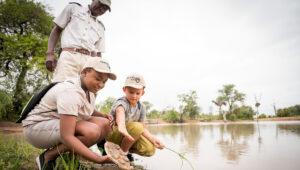 Child and safari guides exploring nature by the water at Kambaku Safari Lodge
