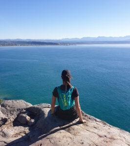 Woman pausing on a coastal hike, overlooking the ocean.