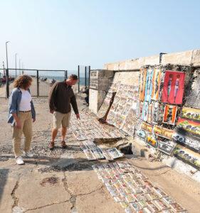 Guests browsing local artwork and paintings at the Kalk Bay outdoor market by the sea.