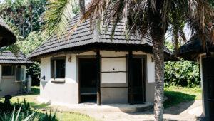 Cosy thatched hut surrounded by palm trees and lush garden at Lambazi Lodge, Wild Coast.