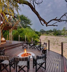 Wooden deck veranda with fire pit at luxury Rhino Post Safari Lodge, overlooking the bush.