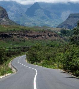 Winding road through green valleys in the Drakensberg Mountains, South Africa.