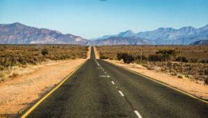 Long straight road stretching toward distant mountains on Route 62, South Africa.