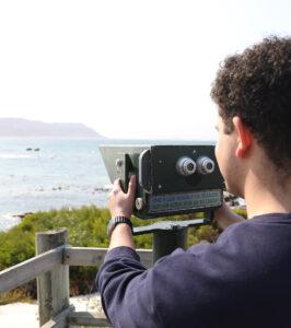 Visitor looking through a coin-operated telescope over the ocean at Cape Point, South Africa.