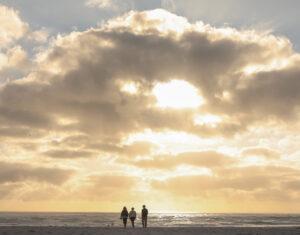 A small group of guests walking along the vast beach of Noordhoek at sunset.