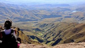 Hiker overlooks vast Amphitheatre, Drakensberg Mountains landscape, South Africa.
