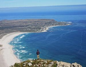 Man looking down on the wide sandy beach of Noordhoek in Cape Town.